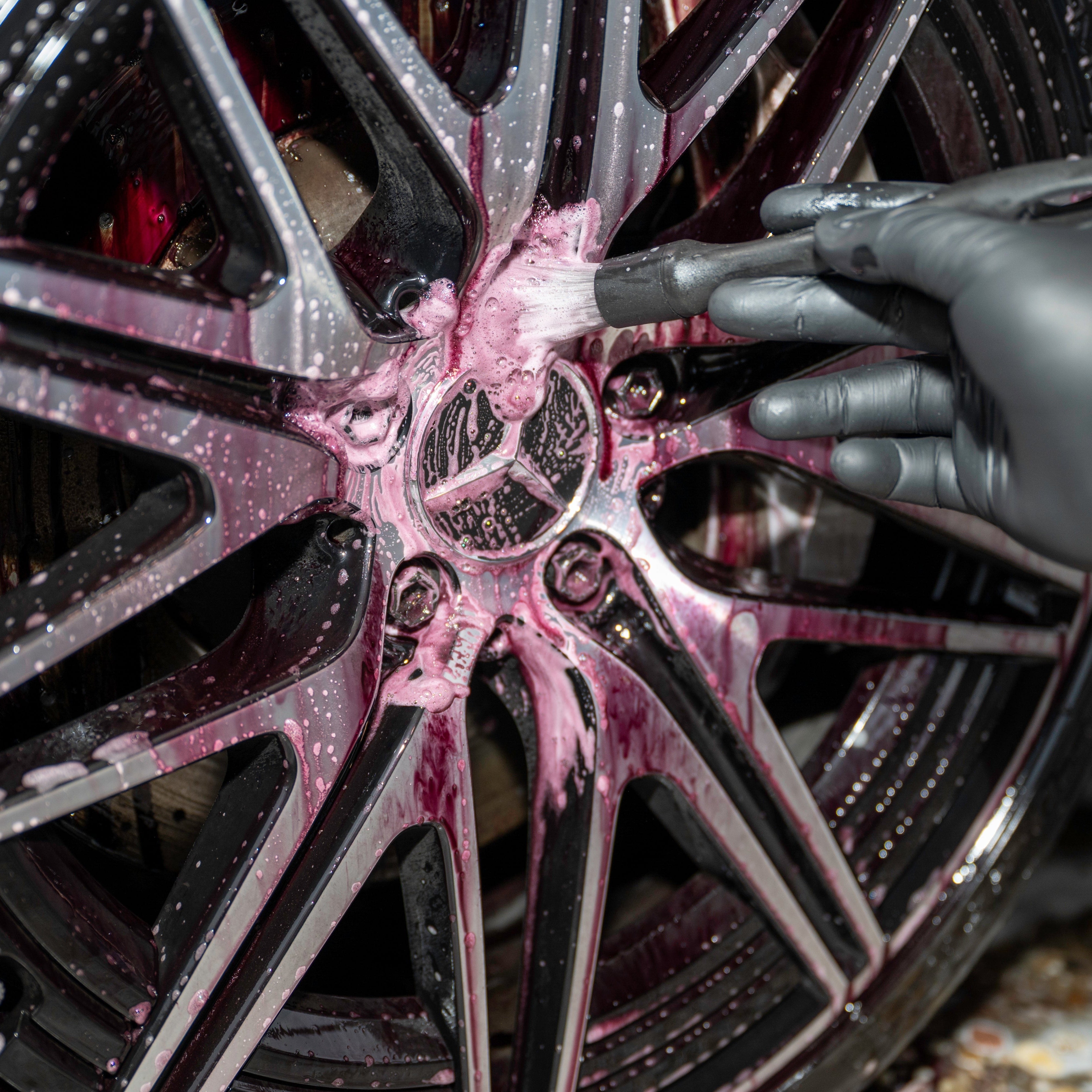 Person cleaning a car wheel with a brush