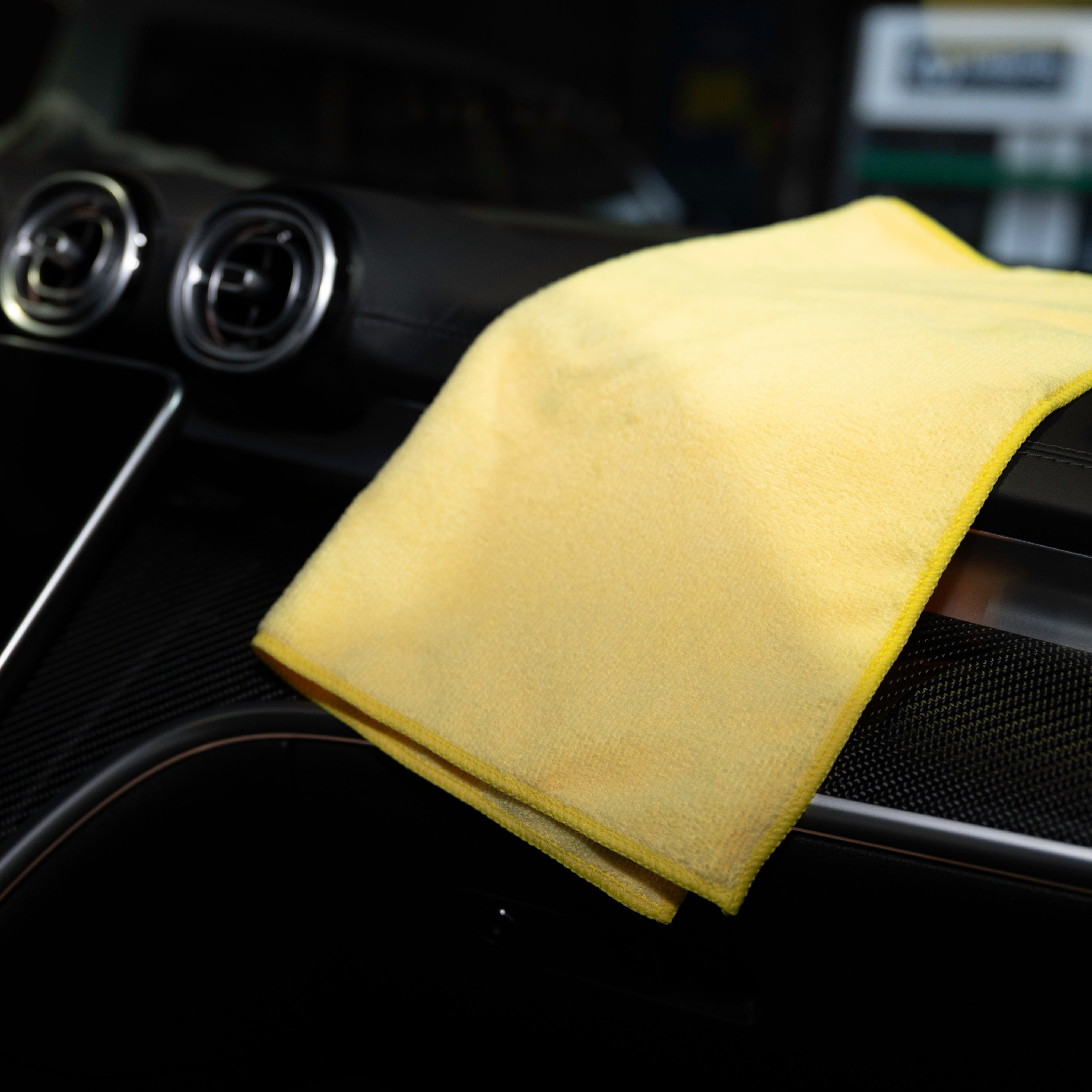 Yellow microfiber cloth on a car's air vent with a blurred background