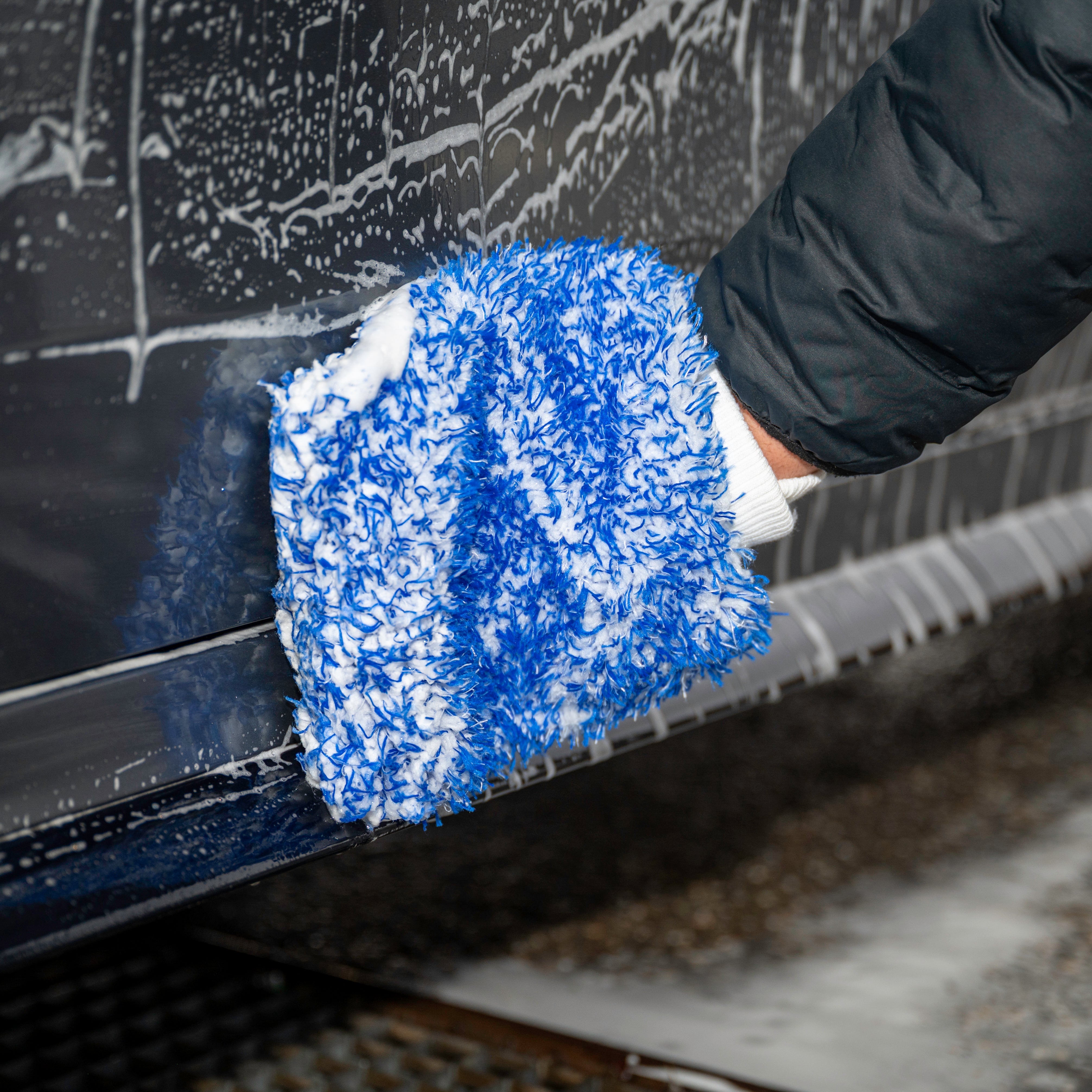 Person cleaning a car with a blue microfiber Wash Mitt.