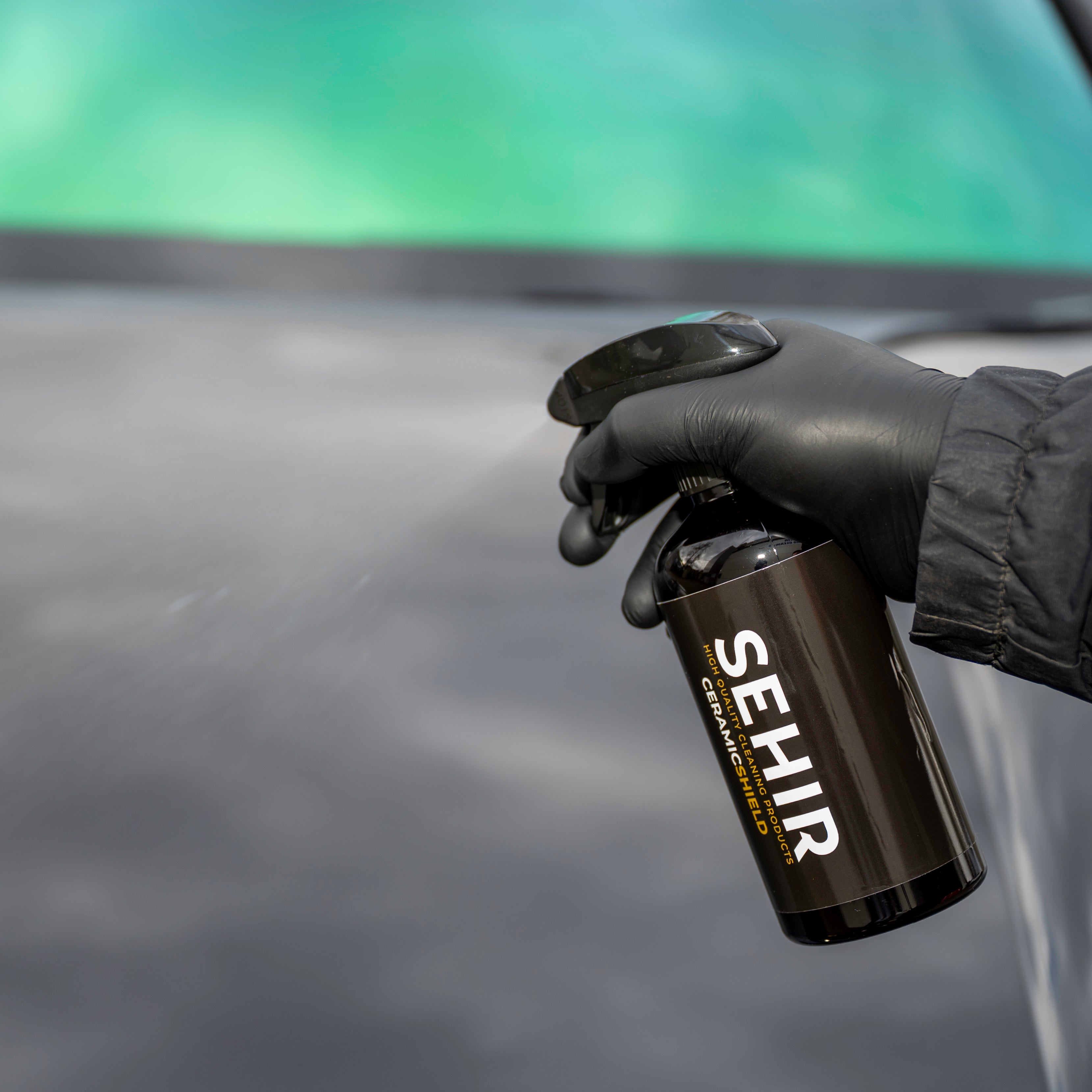Person holding a black spray can labeled 'SEHIR' against a car.