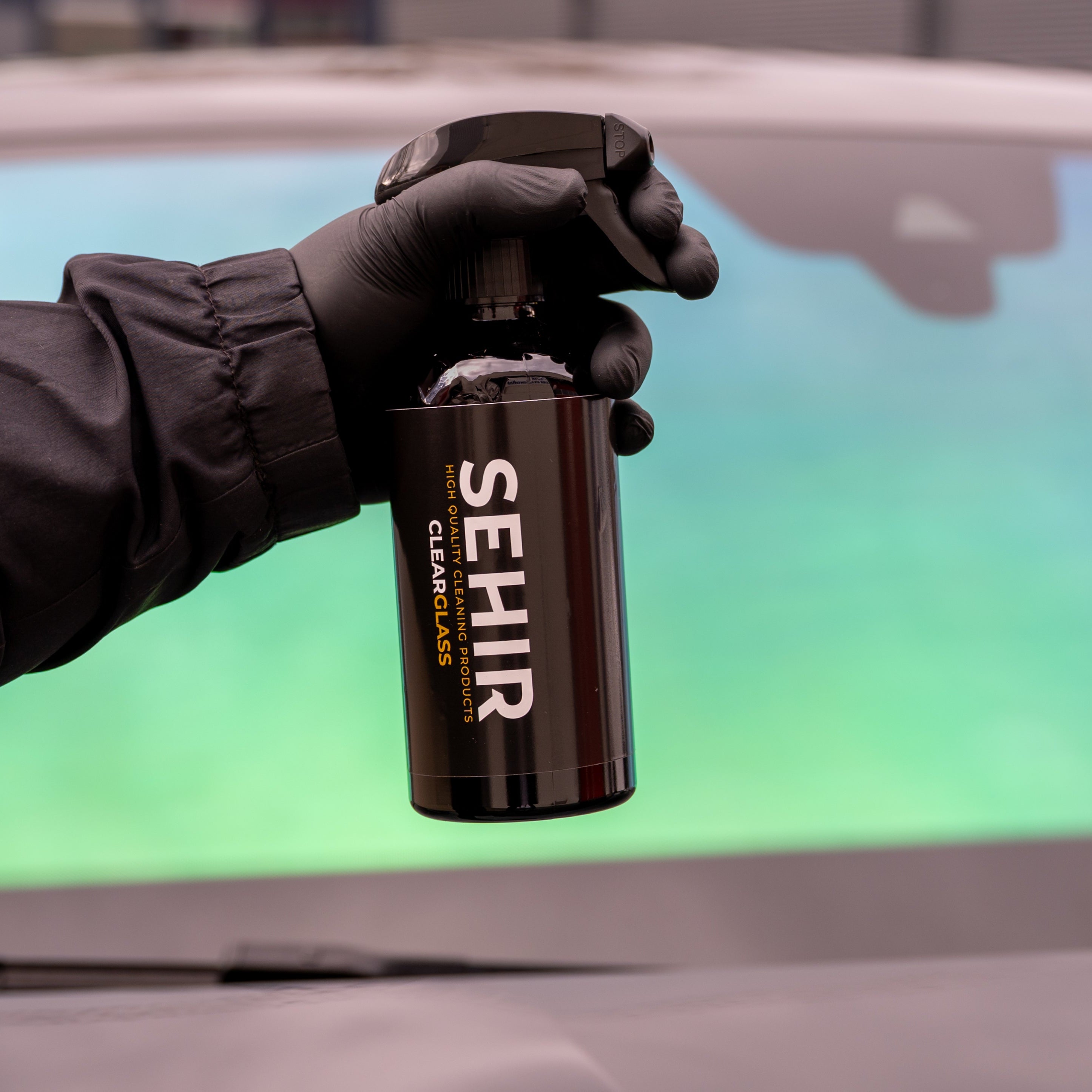 Person holding a can of SEHIR car cleaner in front of a car window.