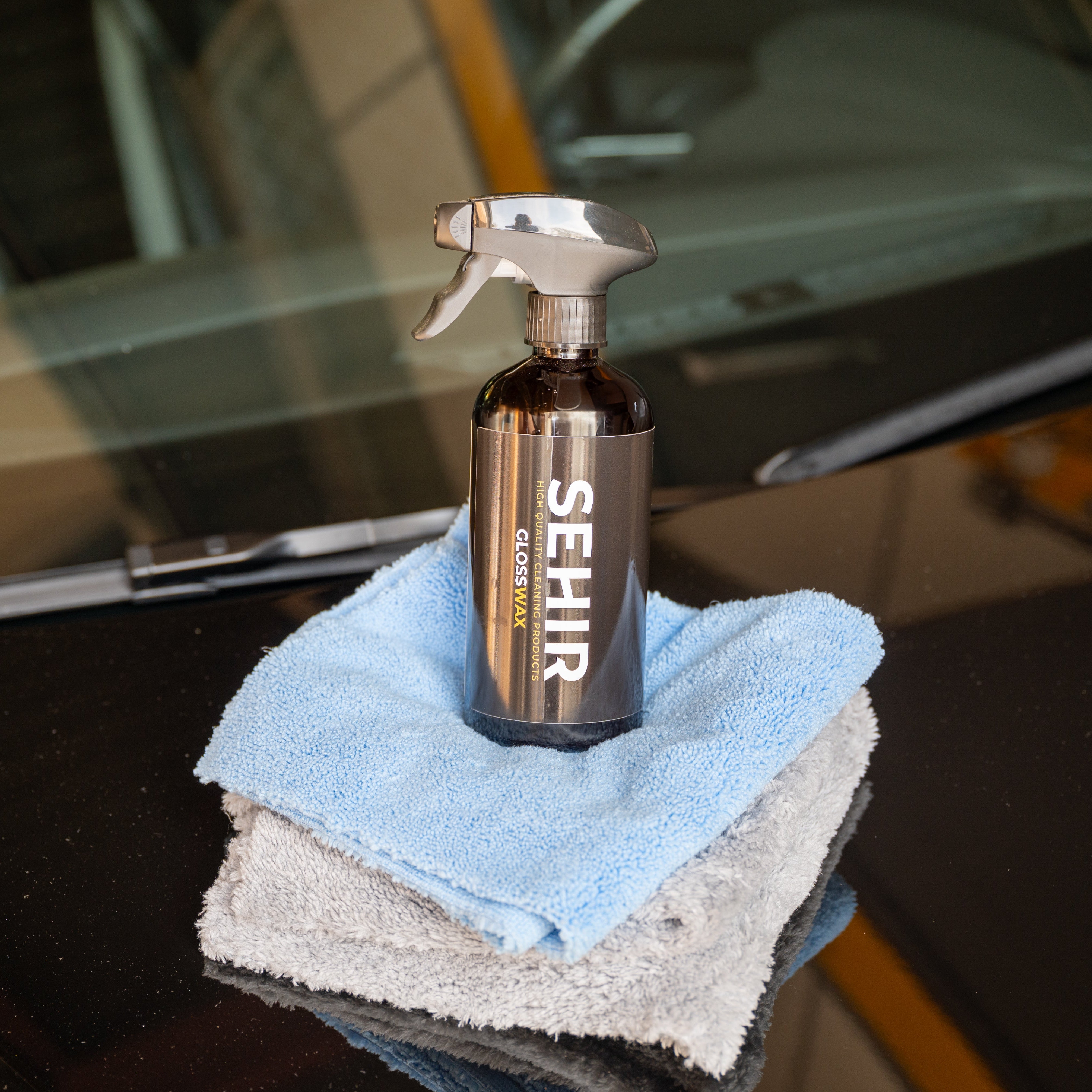Spray bottle labeled 'SEHIR' with cloths on a car window