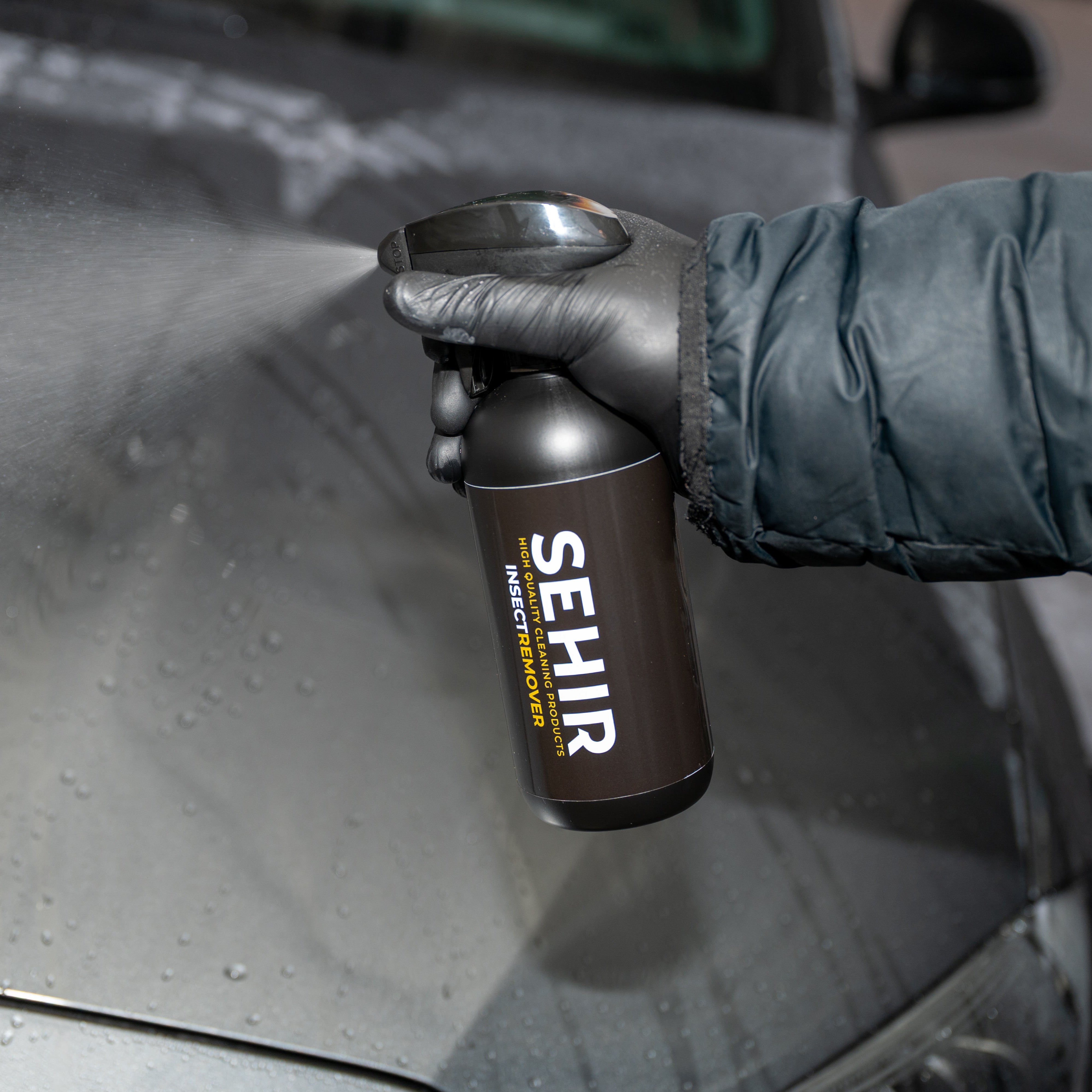 Person holding a can of SEHIR car care product on a car surface