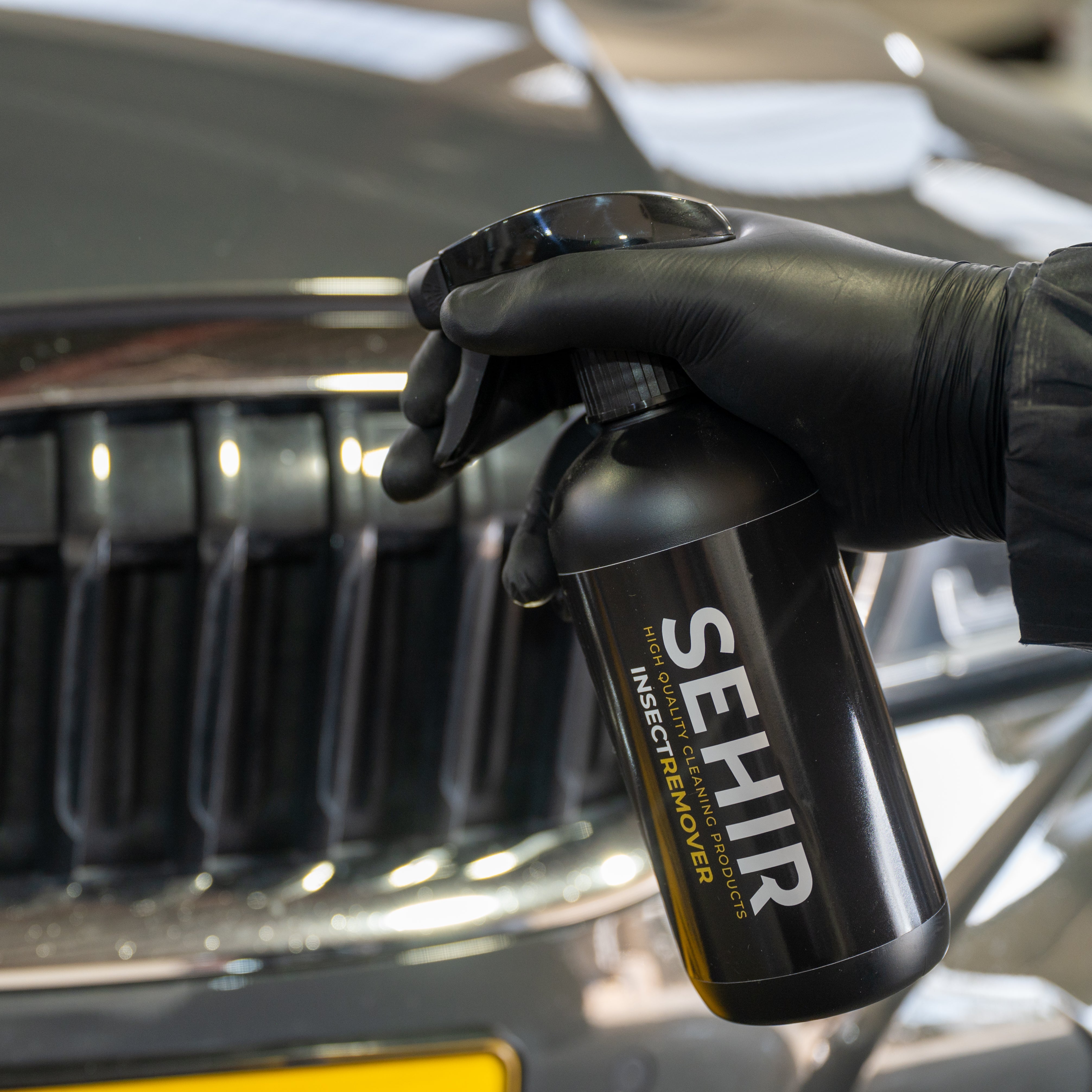 Person holding a SEHIR bottle in front of a BMW car