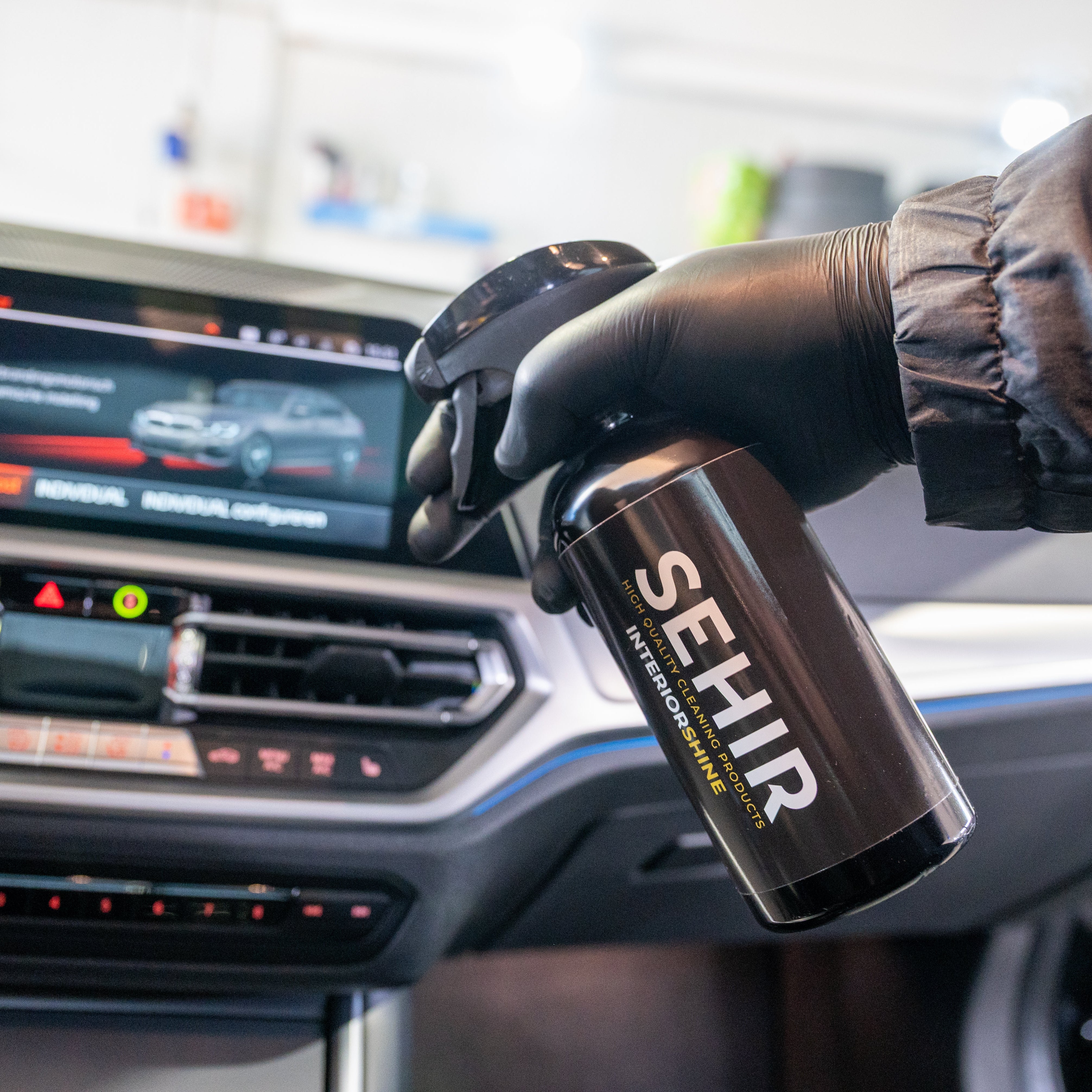 Person holding a can of SEHIR car care product inside a vehicle.