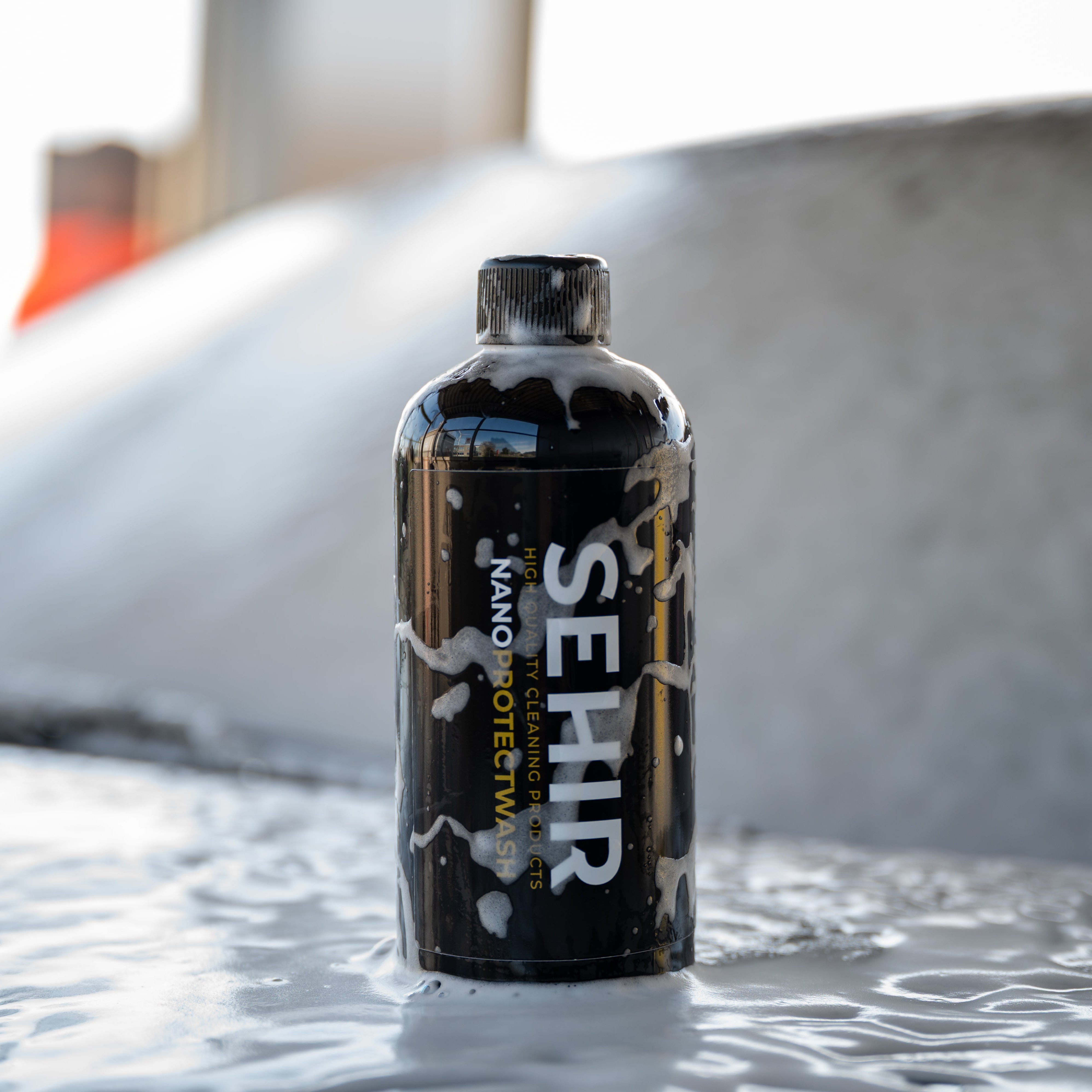 Black bottle labeled 'SEHIR' on a textured surface with a blurred background