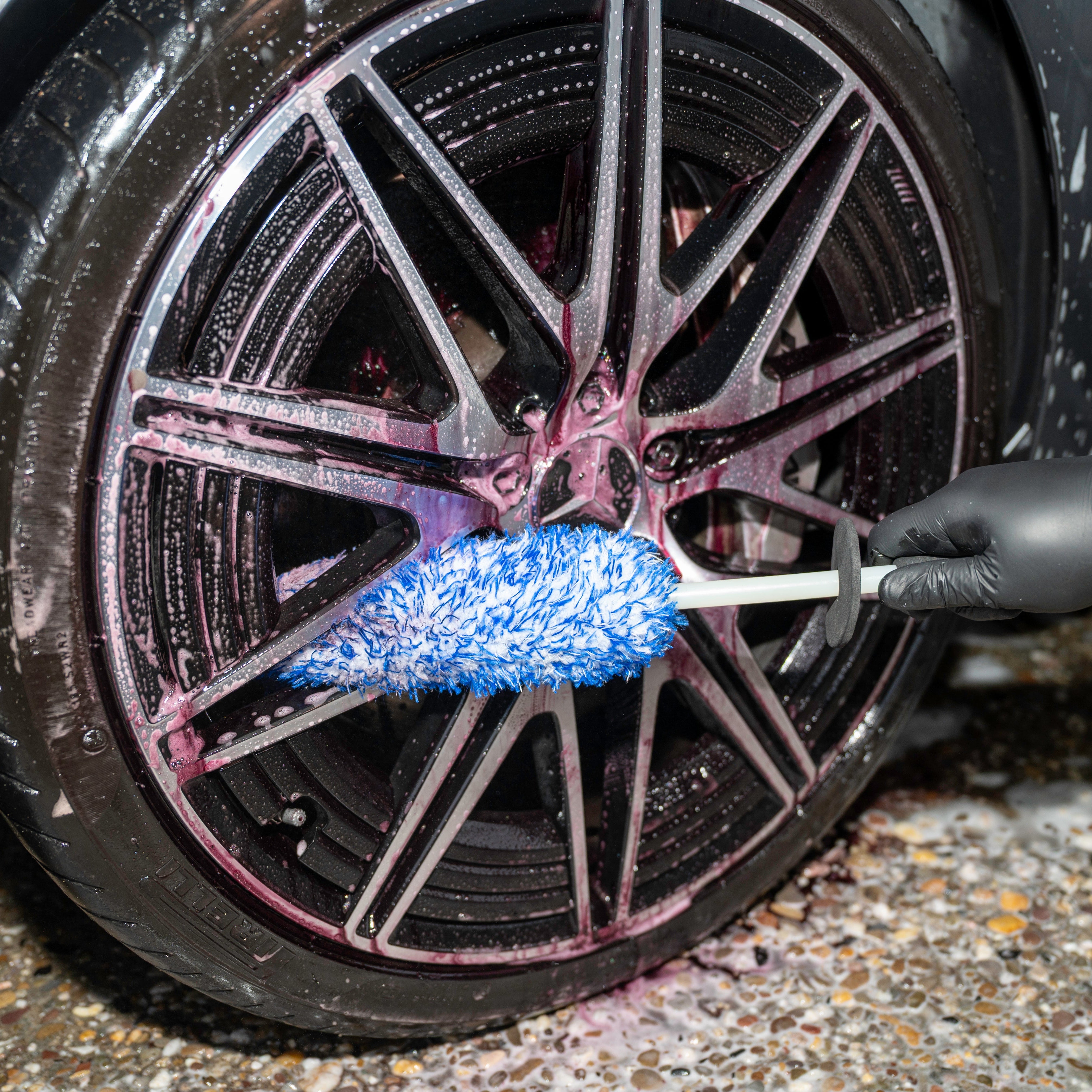 Person cleaning car wheel with a Wheel Brush