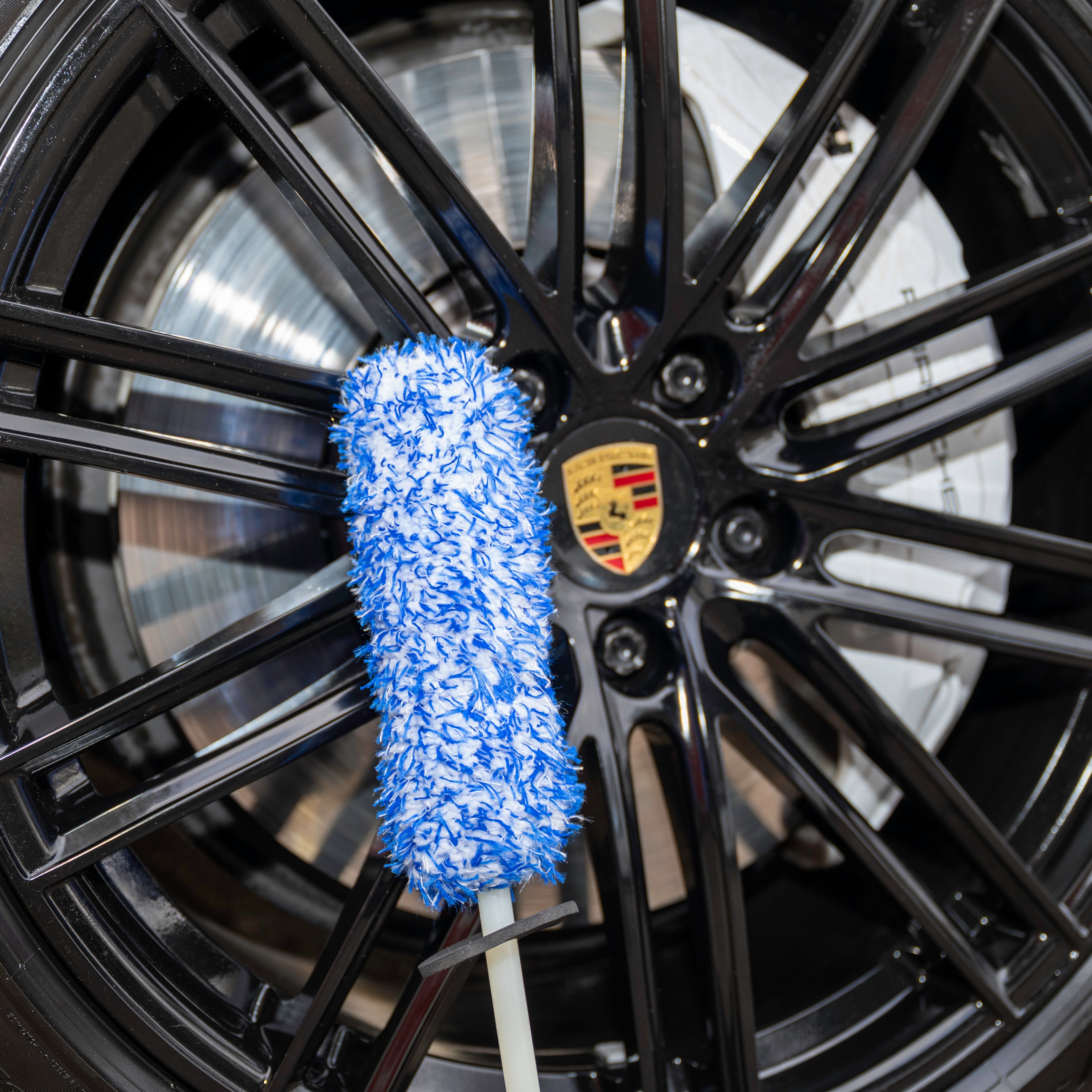 Car wheel with a blue Wheel Brush and Porsche logo