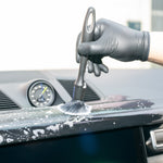 Person cleaning a car's dashboard with a brush and soap solution.