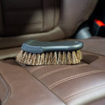 Car interior cleaning brush on a brown leather car seat