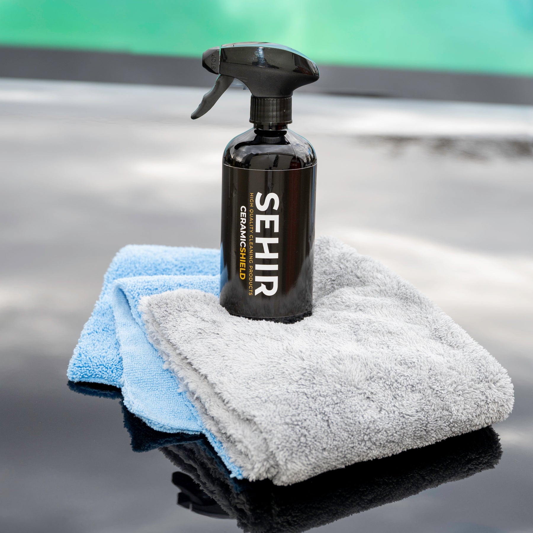 Spray bottle and cloths on a reflective surface with 'SEHIR' branding.