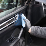 Person cleaning a car's interior dashboard with a white cloth.