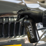 Person holding a SEHIR bottle in front of a BMW car