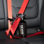 Black bottle with red strap on a car seat