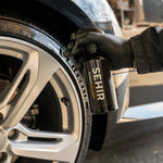 Person shining an tire with a SEHIR spray, close-up view.