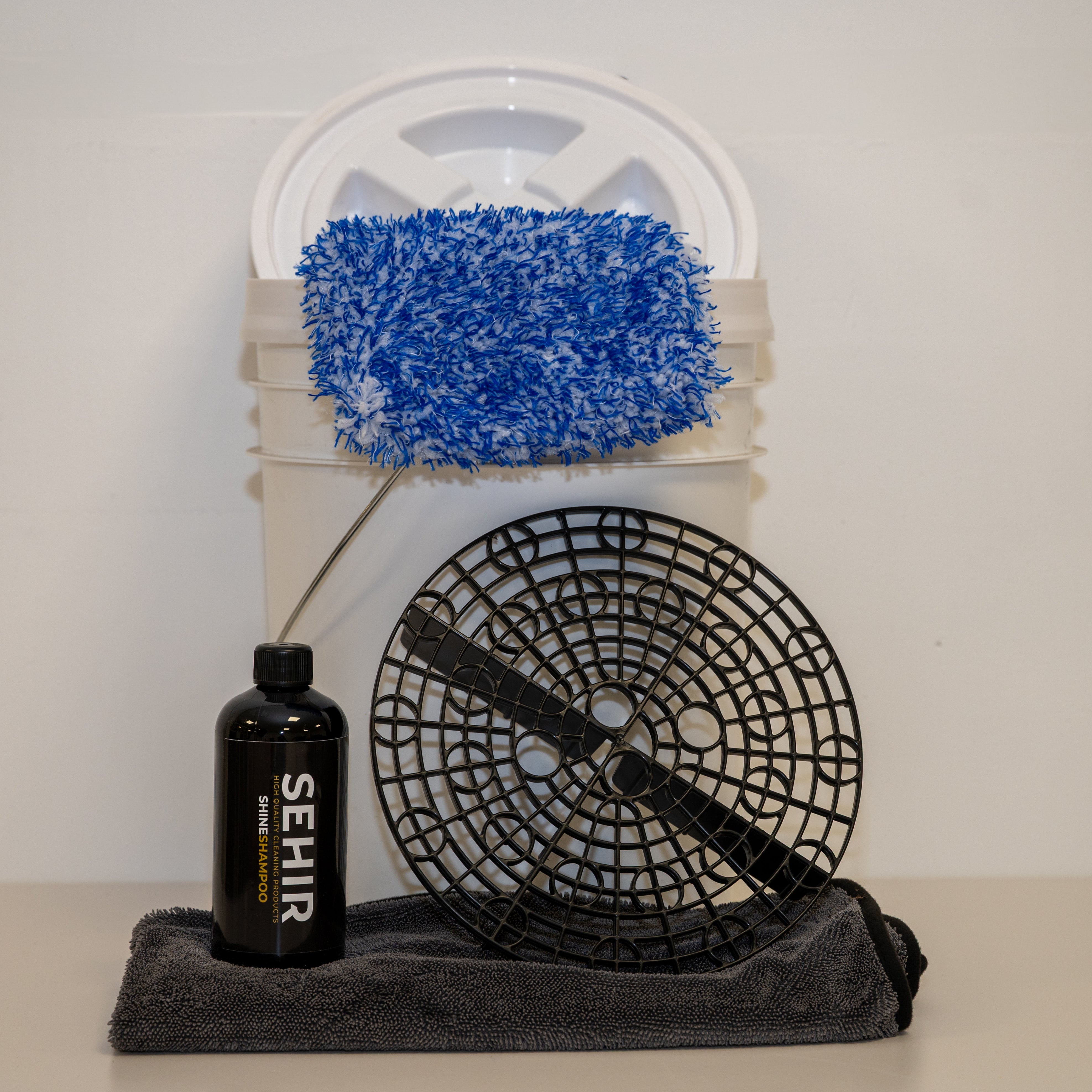 Cleaning tool set with blue scrubber, black bottle, and fan on a white background