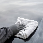 Person cleaning a car with a microfiber cloth