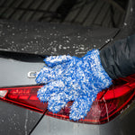 Person cleaning a car's tail light with a blue sponge