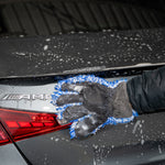 Person cleaning a car's trunk with a blue sponge, featuring an AMG logo.